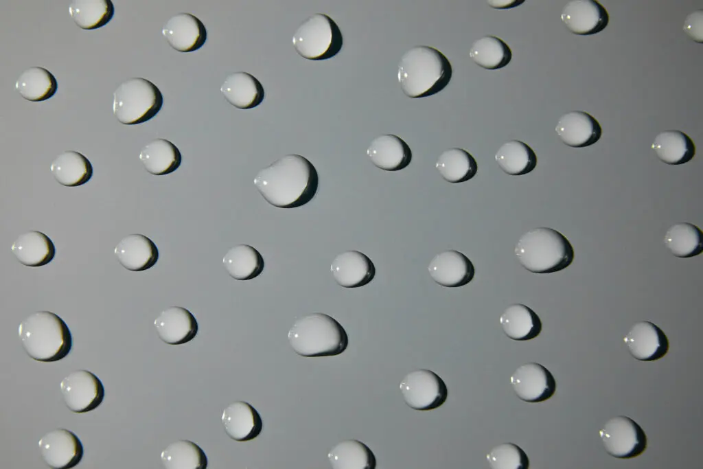 Water droplets on a smooth aluminum surface, demonstrating the waterproof nature of aluminum tread sheets.