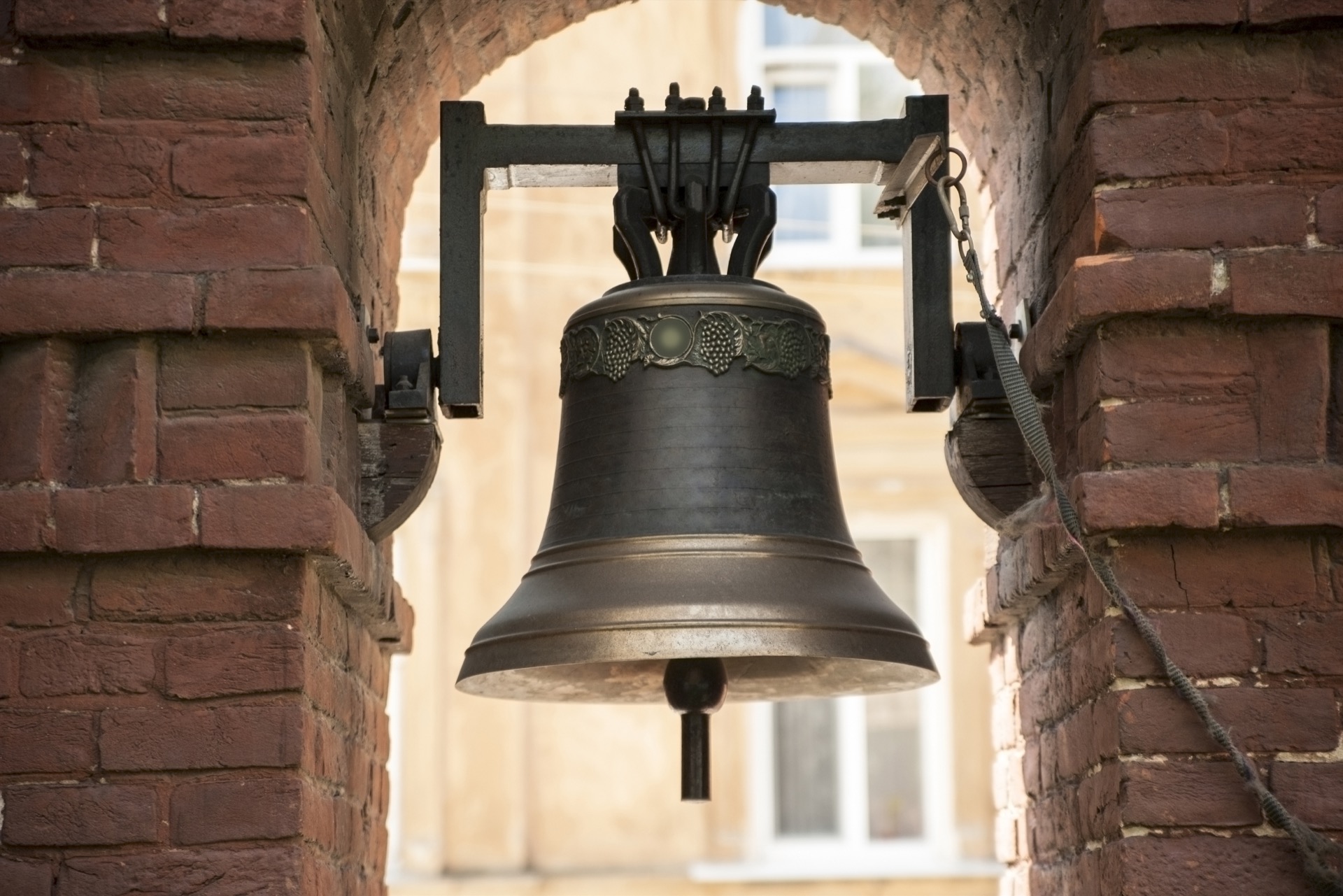 Old bronze bell in between brick