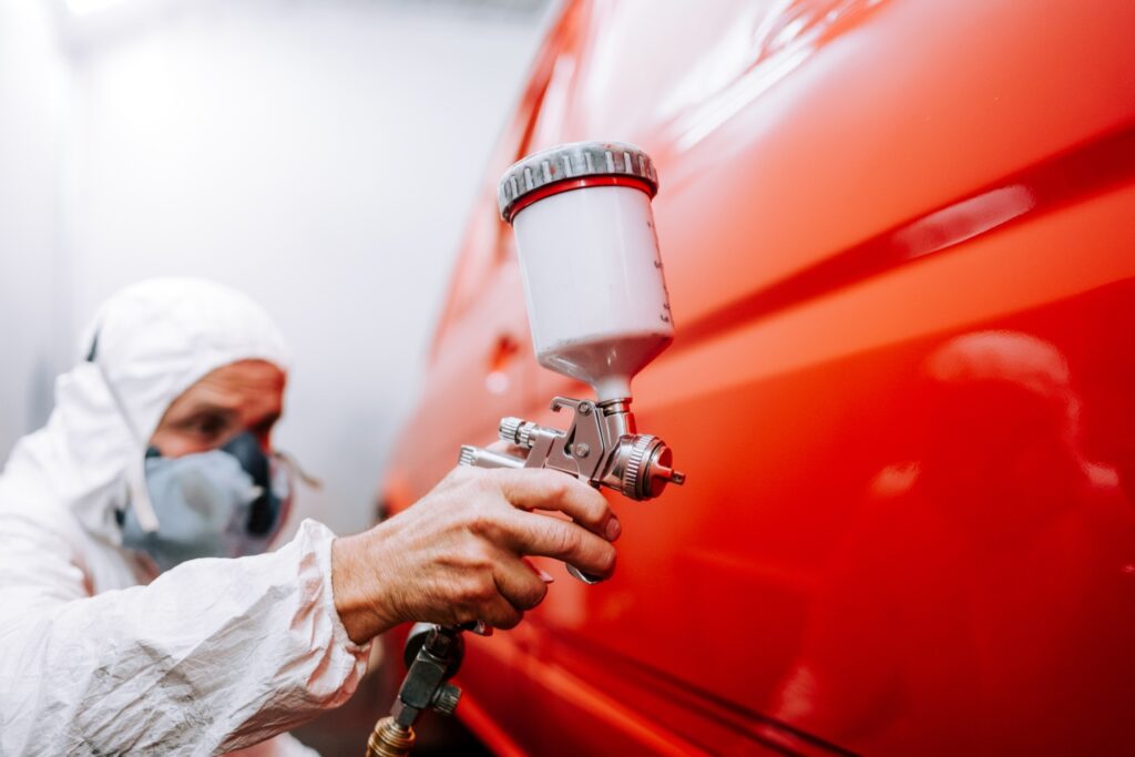 Worker applying new coat of anti-rust paint to car