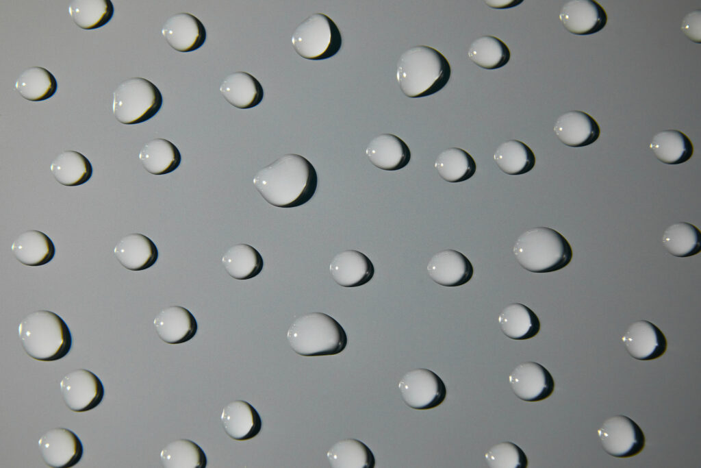 Water droplets on a smooth aluminum surface, demonstrating the waterproof nature of aluminum tread sheets.